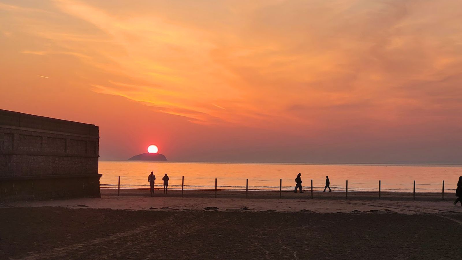 Sunset over Weston-super-Mare seafront with people walking the promenade